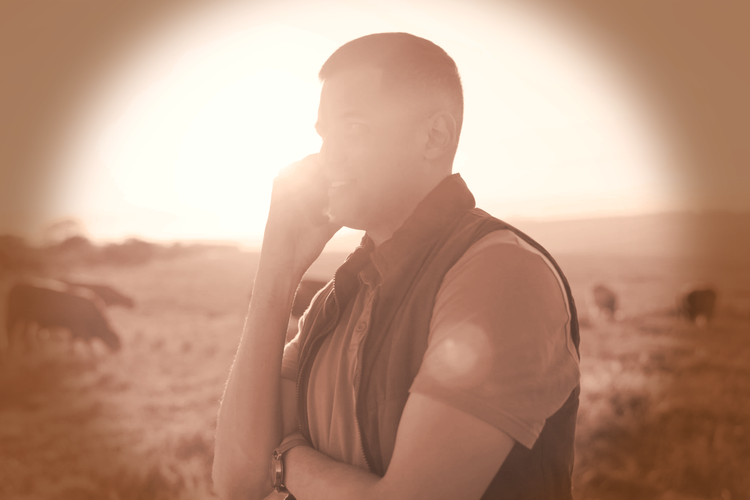 a man on the phone in the middle of a field