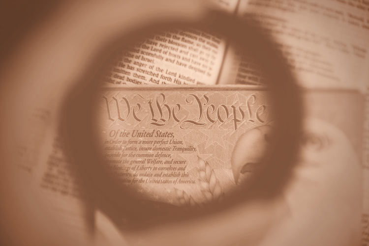 A magnifying glass reading a copy of the United States Constitution