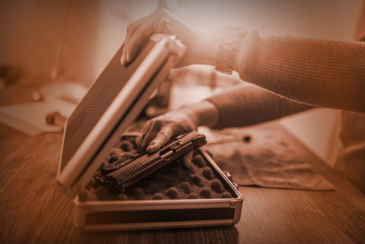 a pair of hands carefully placing a firearm into a safe storage box