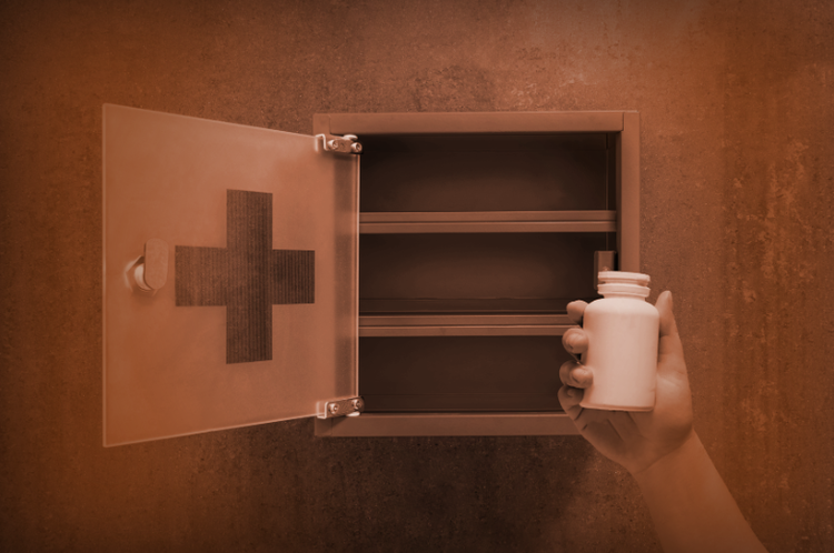 a hand putting a bottle of medicine into a medicine storage lock-box
